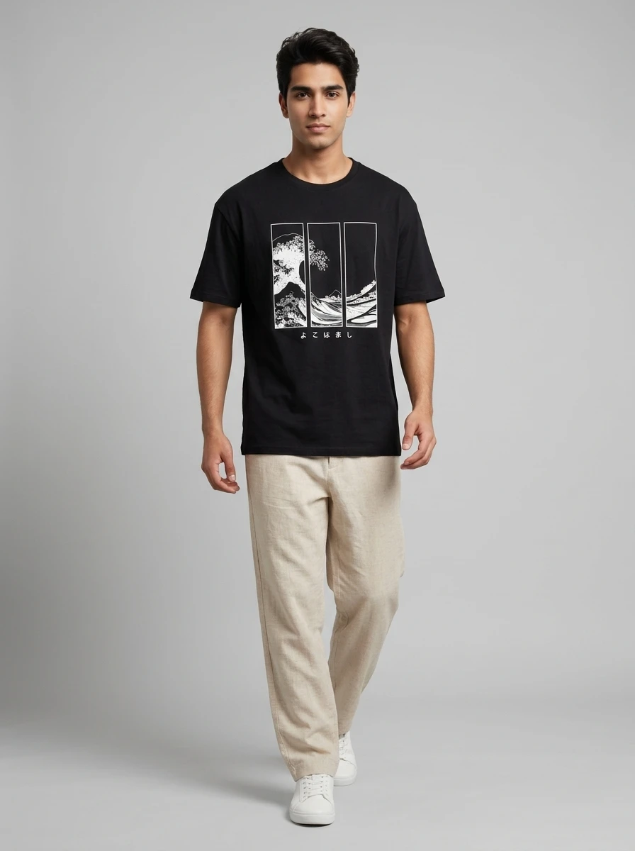 A male model wearing a black t-shirt with a wave graphic and beige trousers against a neutral gray background.