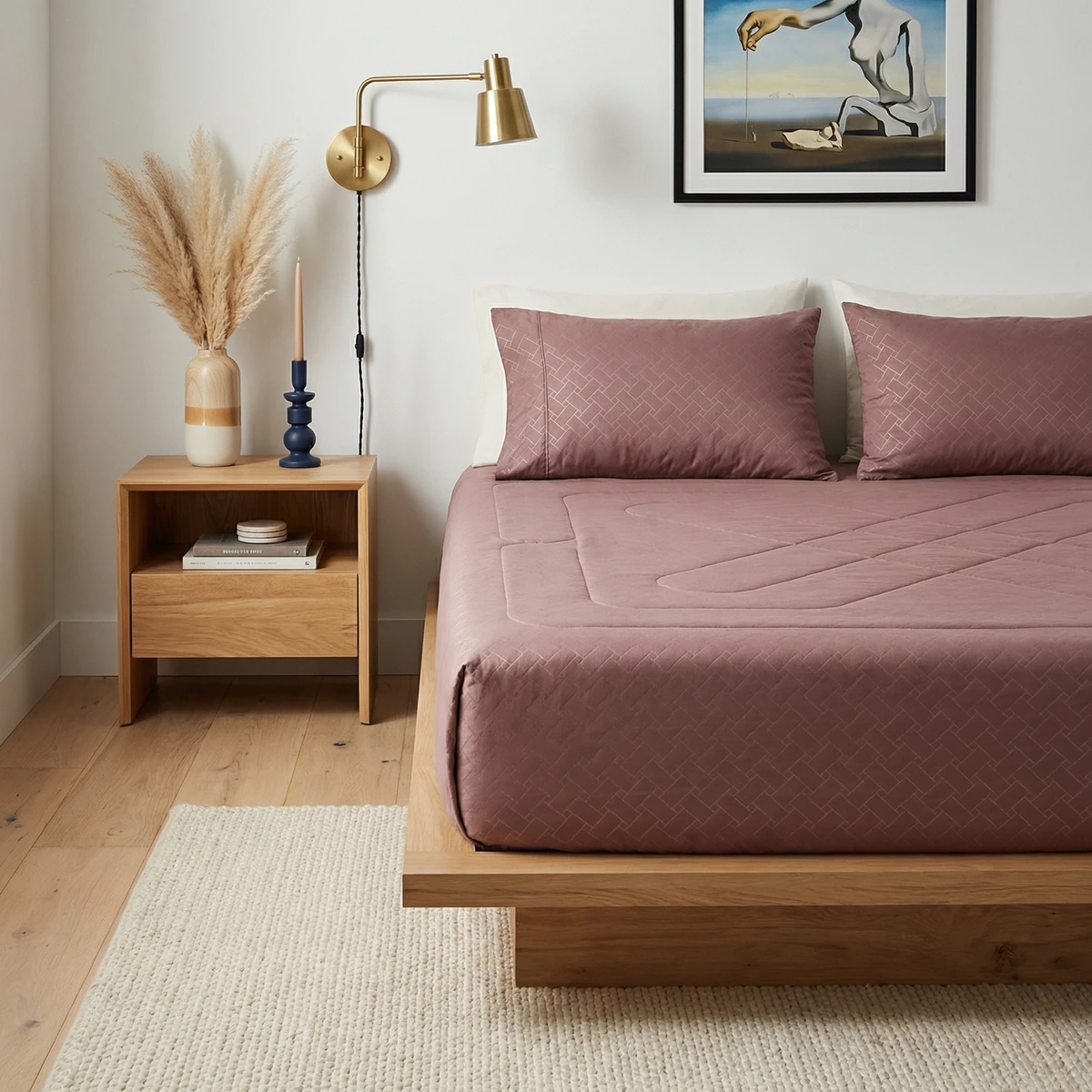 Kanika bed featuring a mauve comforter and matching pillows on a wooden platform frame in a modern bedroom.