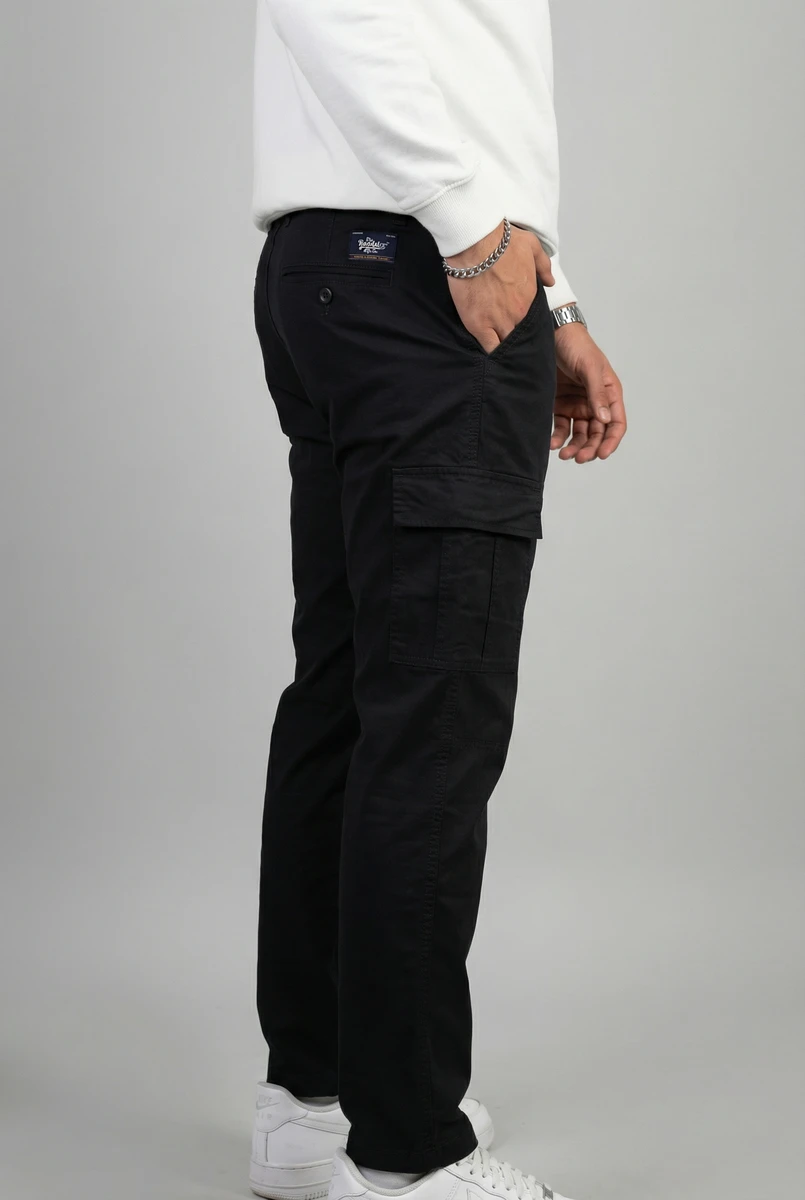 Man wearing black cargo trousers with side pockets and a white sweatshirt, shot from the side against a grey background.