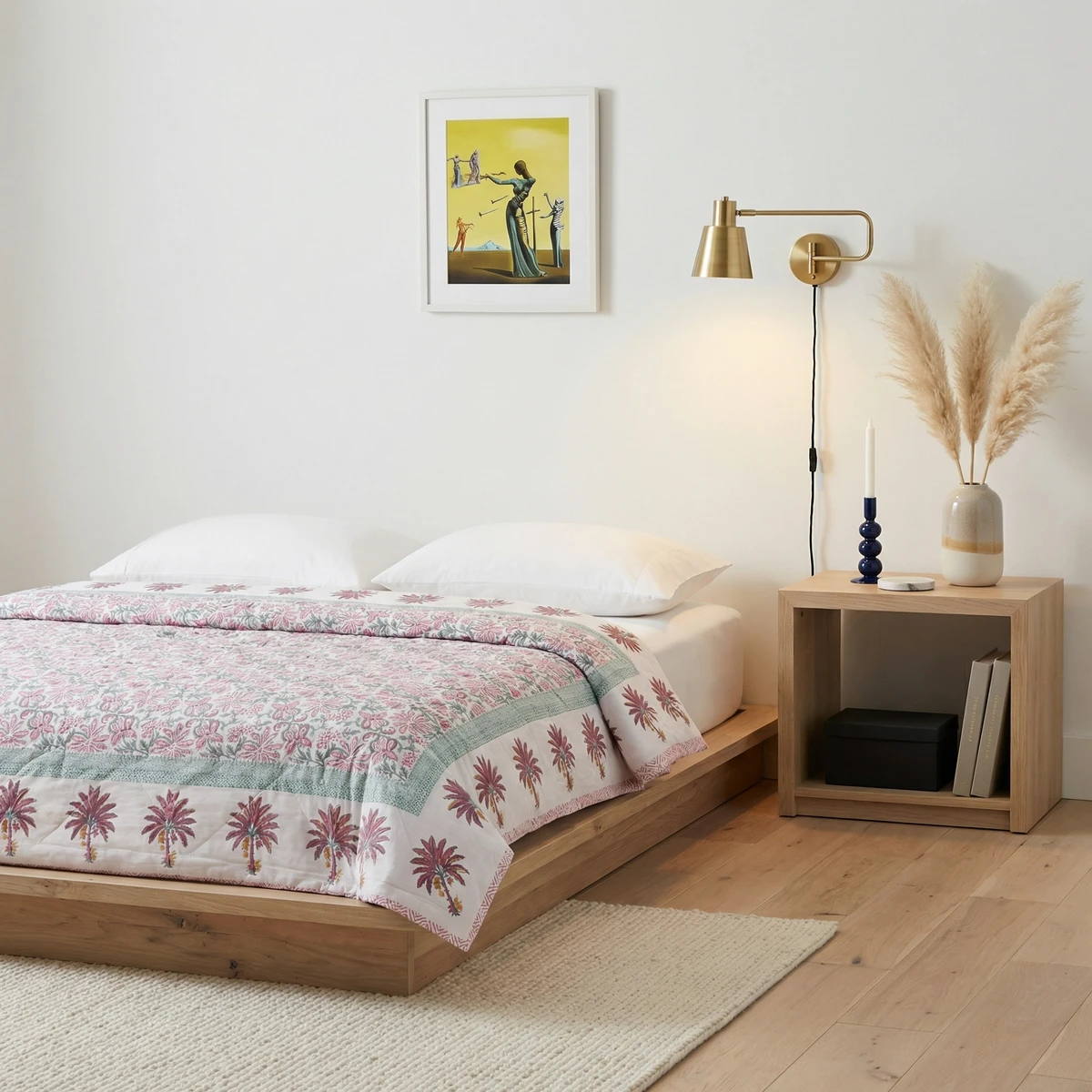 Kanika comforter with pink floral and palm tree print on a wooden platform bed in a minimalist bedroom.