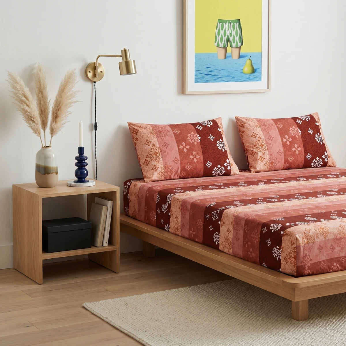 Kanika bed sheet in red and pink tones with intricate patterns on a wooden platform bed.