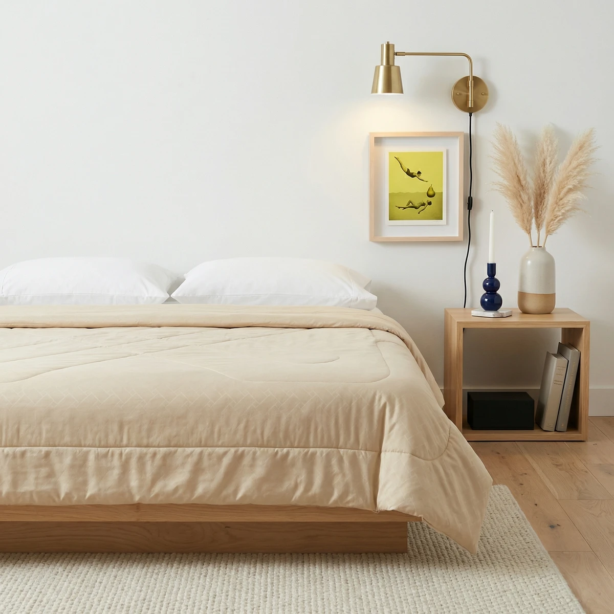 Beige comforter on a wooden bed in a bright bedroom with white pillows and a nightstand.