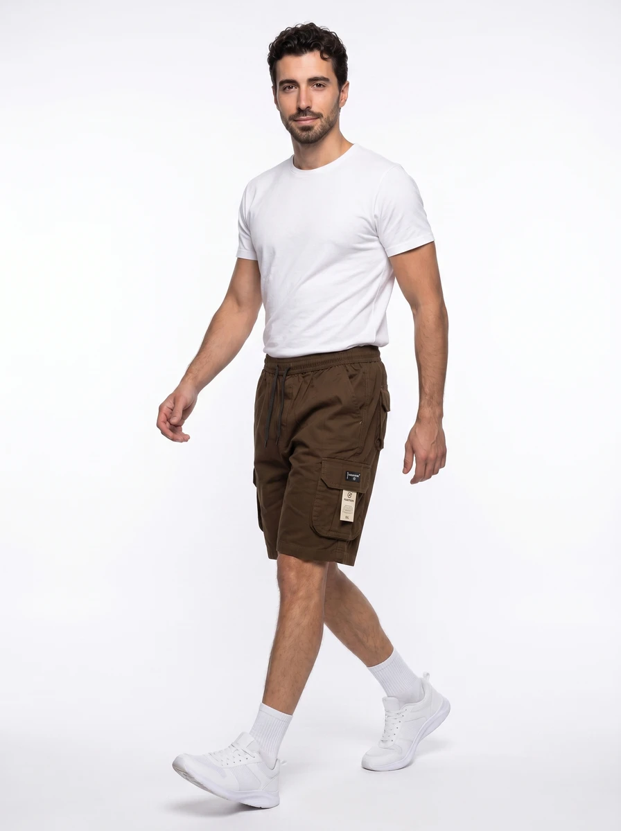 A male model wearing a white t-shirt and brown cargo shorts walks against a white background.
