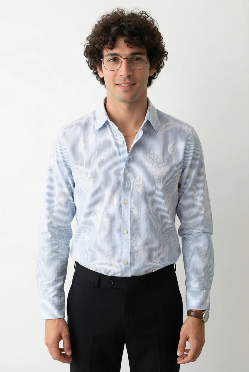 A male model wearing a light blue and white patterned long-sleeve shirt paired with black trousers against a plain background.