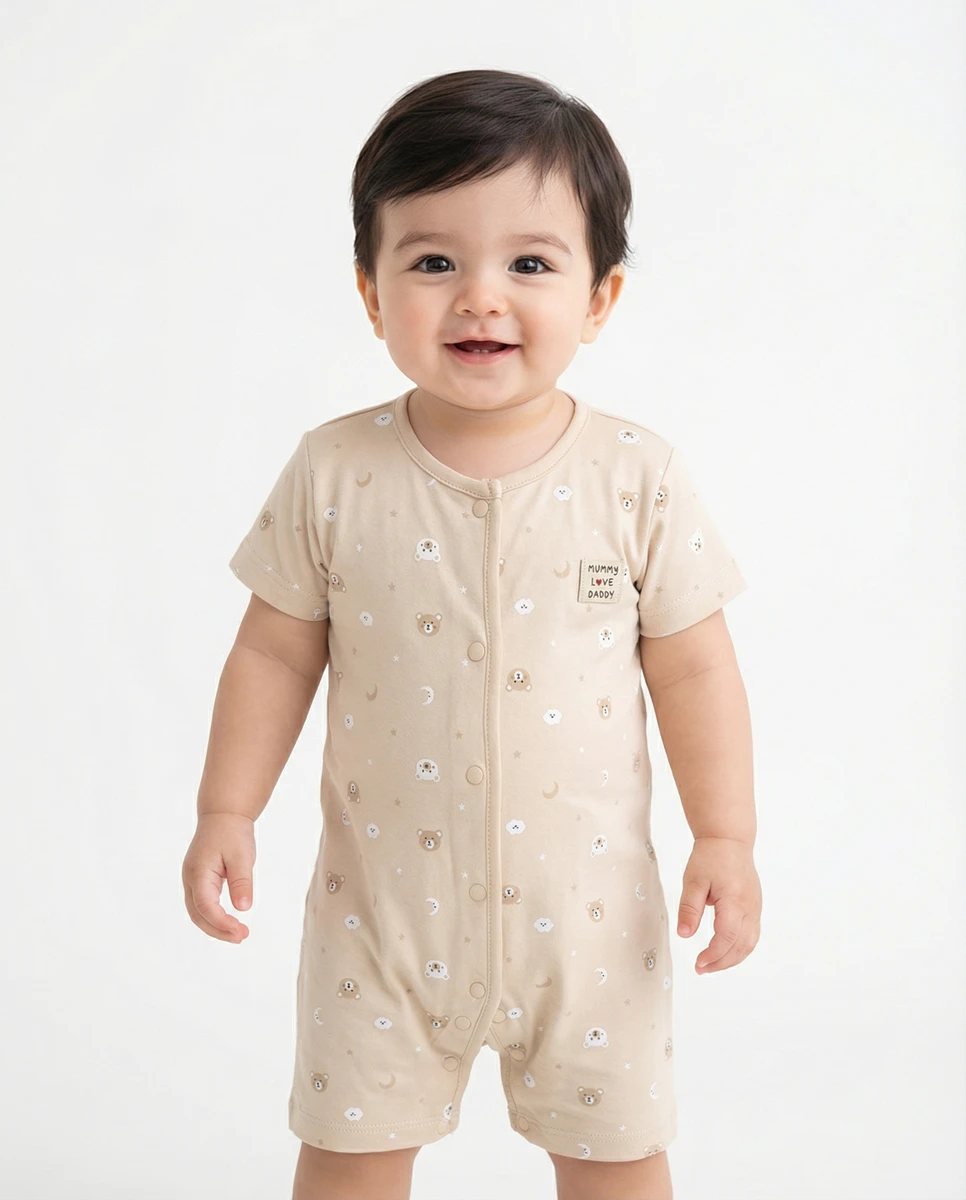 Toddler model wearing a short-sleeve beige romper with a bear print against a white studio background.