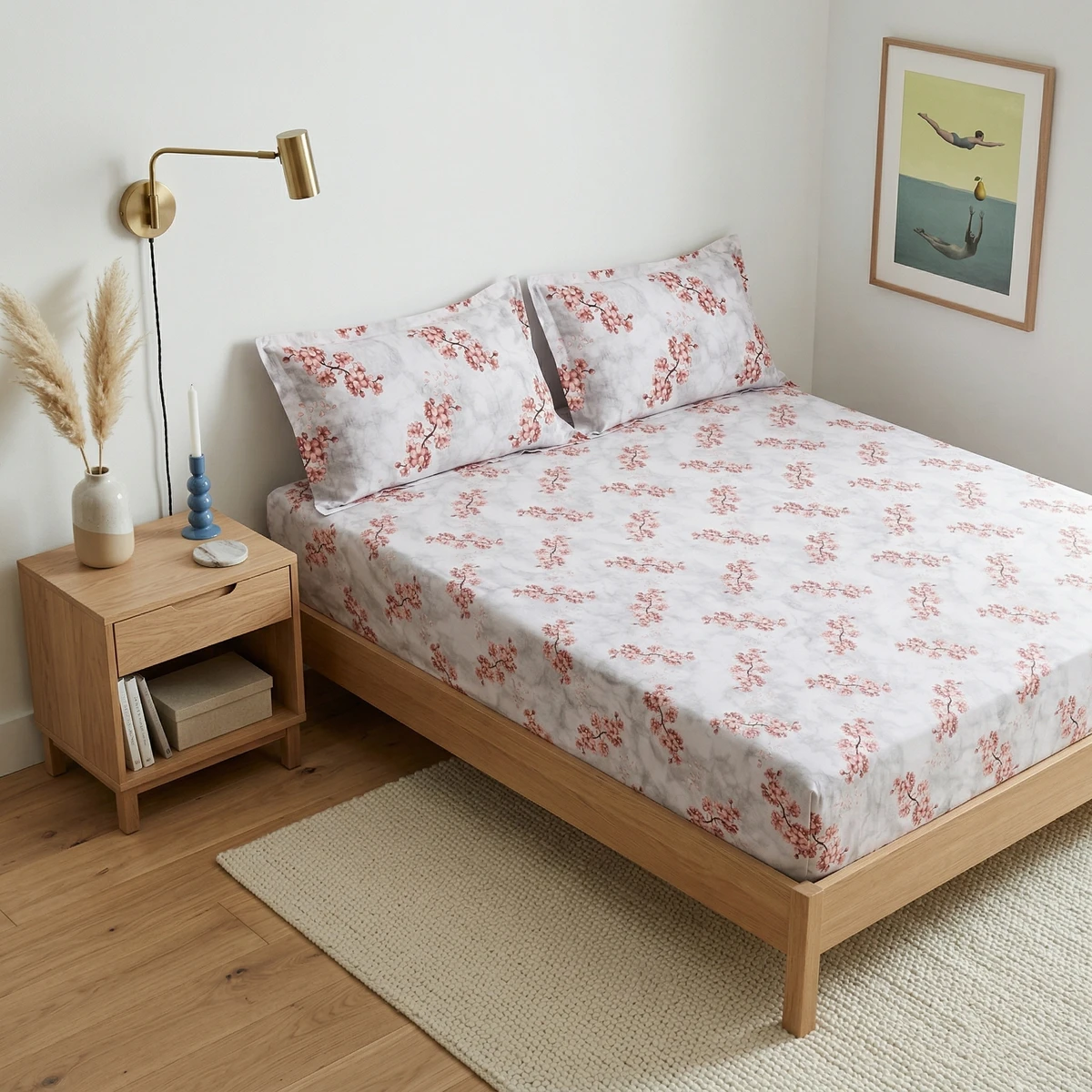 White bed sheets with a grey marble pattern and pink cherry blossom print on a wooden bed frame.