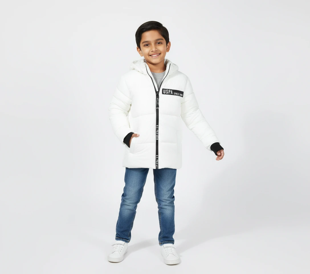 Young boy wearing a white hooded puffer jacket with black details and blue jeans.