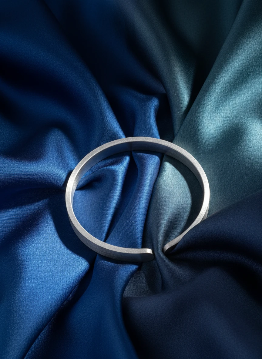 Studio AI flat-lay photoshoot of a silver bracelet on blue silk, for a bracelet brand selling on marketplaces