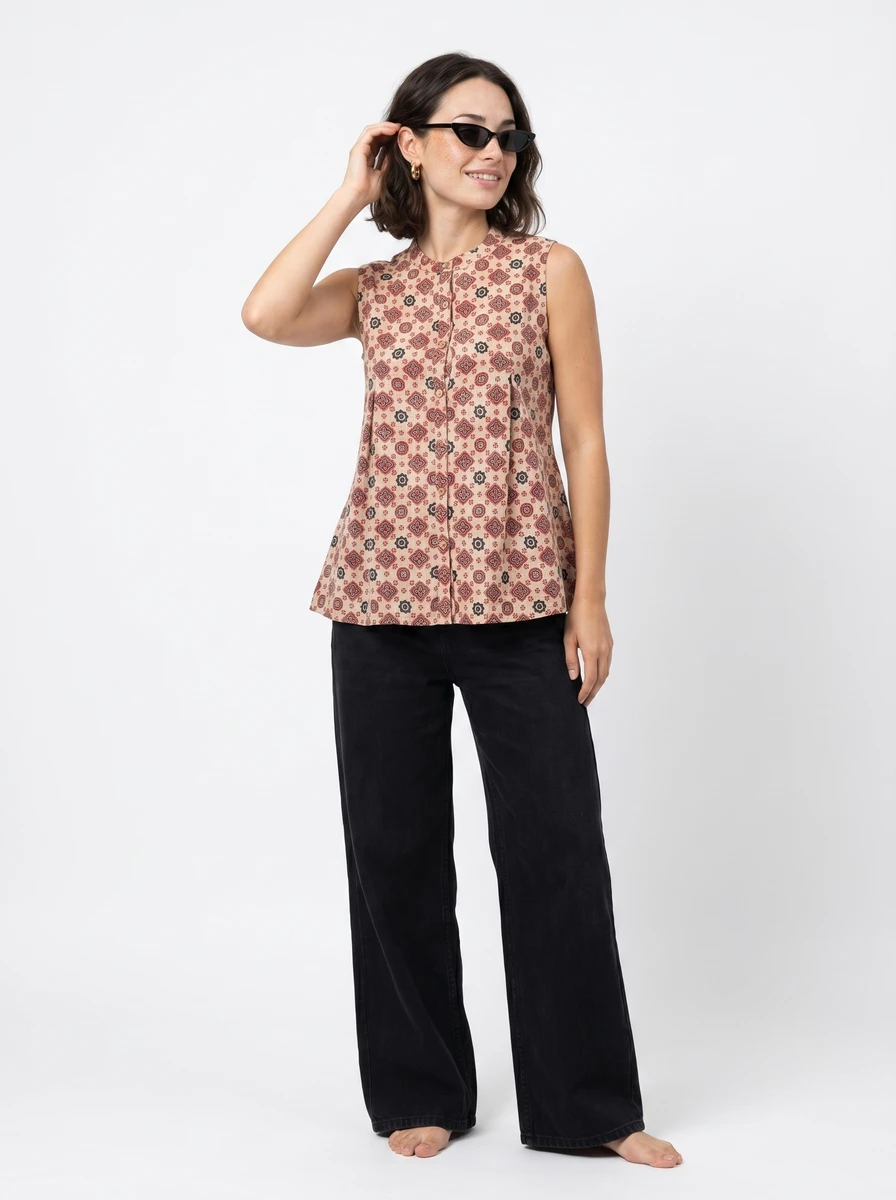Model wearing a patterned sleeveless blouse and black wide-leg pants against a plain white studio background.