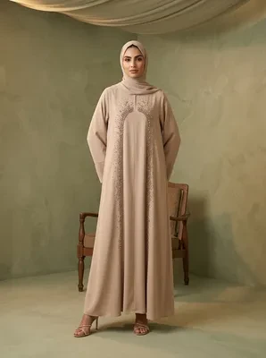 Model standing in a long beige Dubai abaya featuring delicate beadwork along the front, paired with a matching hijab.