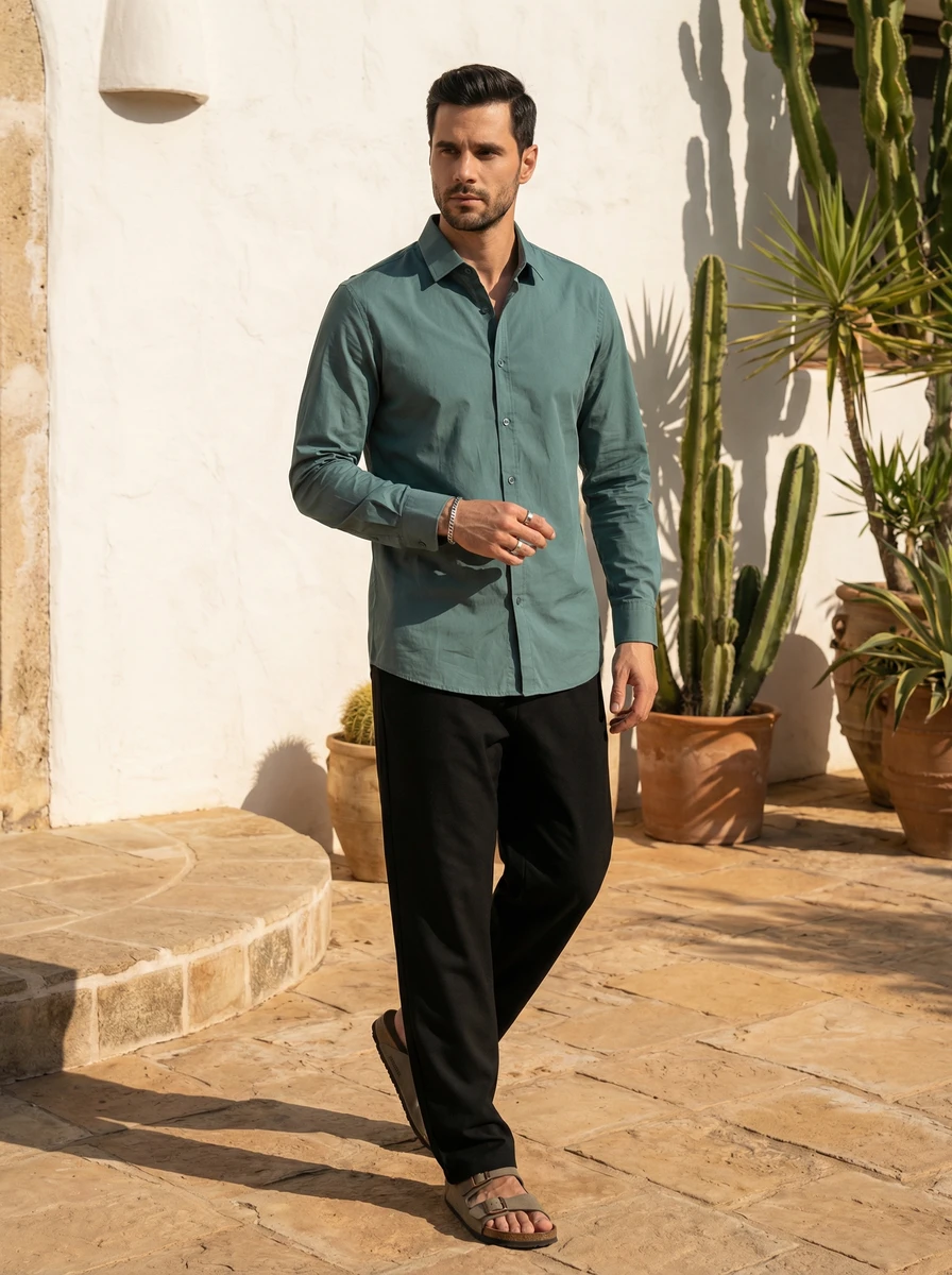 Man wearing a teal long-sleeve button-down shirt and black trousers outdoors.